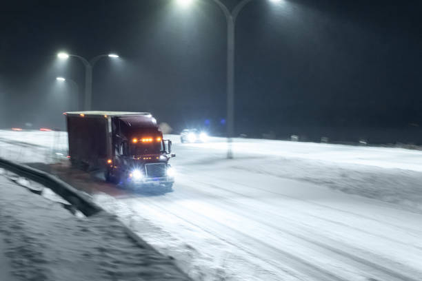 Semi truck on a multi lane highway during heavy snowfall at night. Photographed at high iso with slight motion blur in some points of the frame.