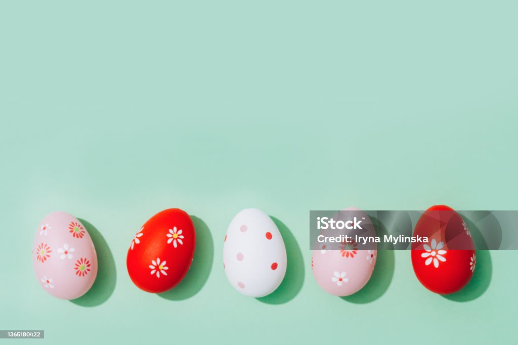 Easter greeting card - red and pink Easter eggs on pastel mint background with copy space for text. Flat lay, selective focus Easter greeting card - bright red and pink Easter eggs on pastel mint background with copy space for your text. Flat lay. Selective focus Easter Egg Stock Photo