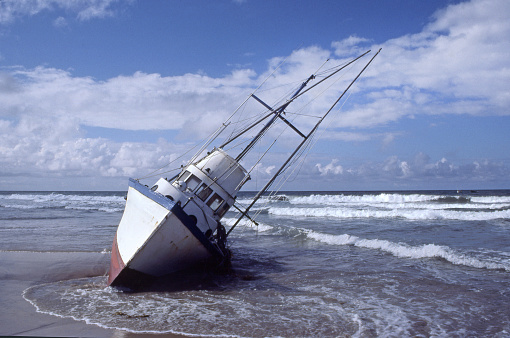 A fishing boat lists as it sits grounded in the surf.