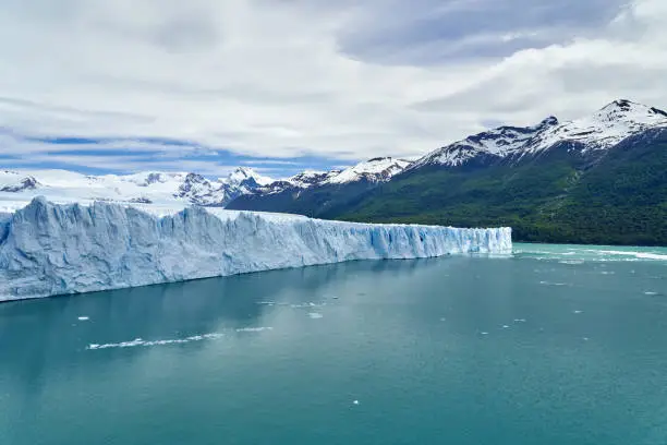 Blue ice of Perito Moreno Glacier in Glaciers national park in Patagonia, Argentina with turquoise water of Lago Argentino in the foreground, dark green forests and sow covered mountains of the Andes in the distance_4