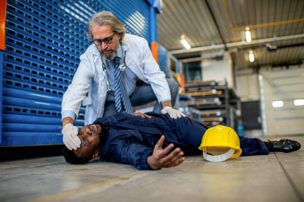 Doctor examining injured worker in factory stock photo