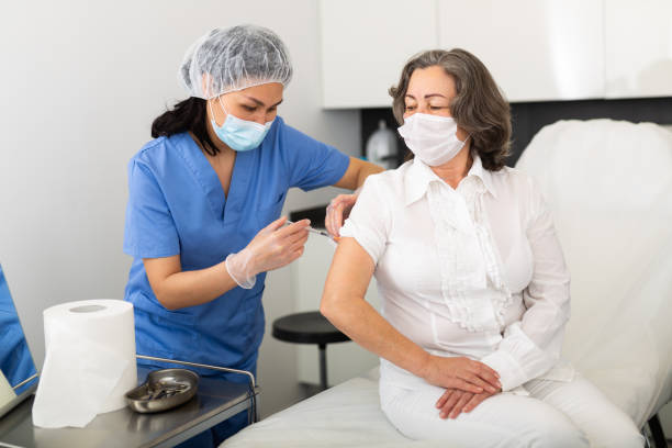 istock Focused general practitioner vaccinating elderly female patient 1365188894