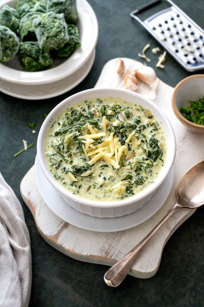 istock Creamed spinach with garlic and cheese in a white bowl on dark background. 1365189951