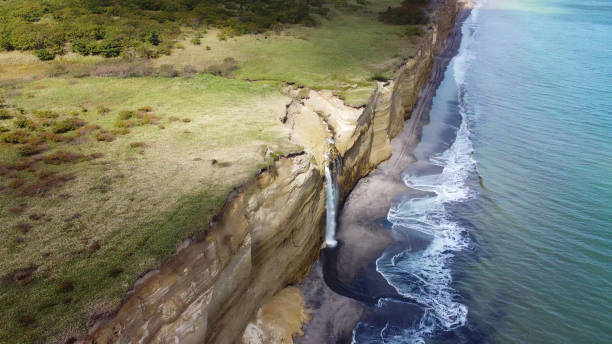 Waterfall on Golovinsky Cliff on Kunashir Island, Kuril Islands, Russia. Aerial view. Waterfall on Golovinsky Cliff on Kunashir Island, Kuril Islands, Russia. Aerial photography. kunashir island stock pictures, royalty-free photos & images