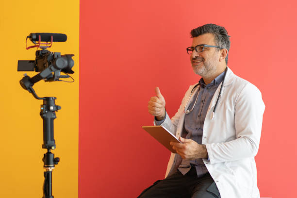 Pediatrist doctor with digital tablet while vlogging against colored background stock photo