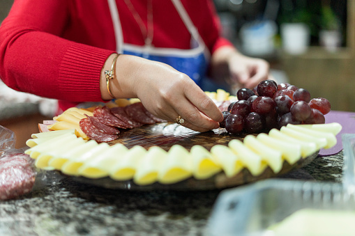 Latin woman from Bogotá - Colombia prepares a delicious cheese board in the kitchen of her home