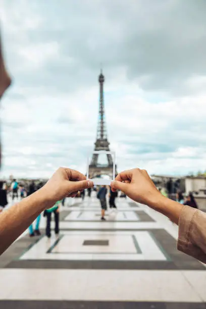Couple traveling to Paris take a picture in front of the Eiffel Tower.