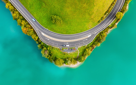 The road near turquoise lake. Aerial landscape. The road by the lake in Switzerland. Summer landscape from the air. Forest and road with curves.