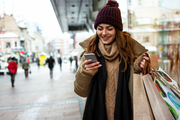 Beautiful woman using mobile phone during shopping in wintertime