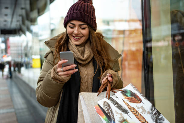 istock Beautiful woman using mobile phone during shopping in wintertime 1365210697
