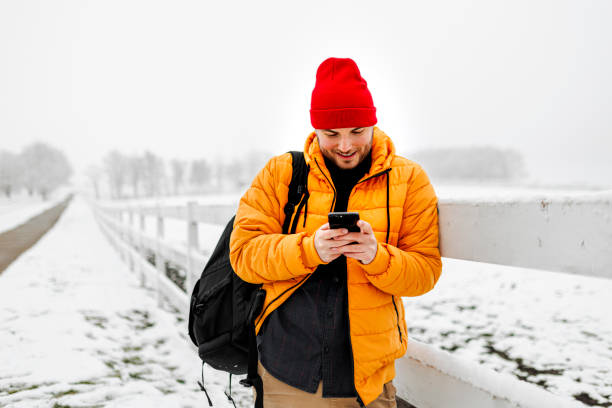 istock Young man using smartphone in nature on a snowy day 1365210973
