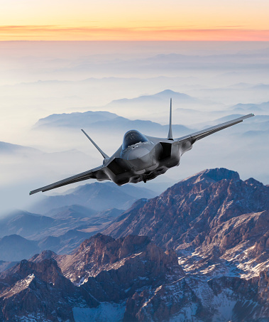 Fighter Jet flying over mountains at sunset