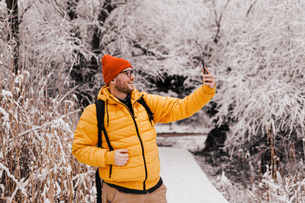 istock Handsome young man having video call (making a selfie) in snowy nature 1365211309