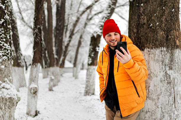 istock Young man using smartphone in nature on a snowy day 1365211881
