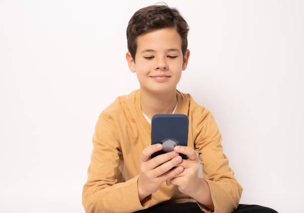 istock Caucasian boy in casual clothing using smartphone isolated over white background. 1365213104