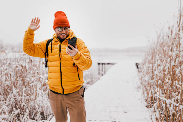 istock Handsome young man having video call (making a selfie) in snowy nature 1365213115