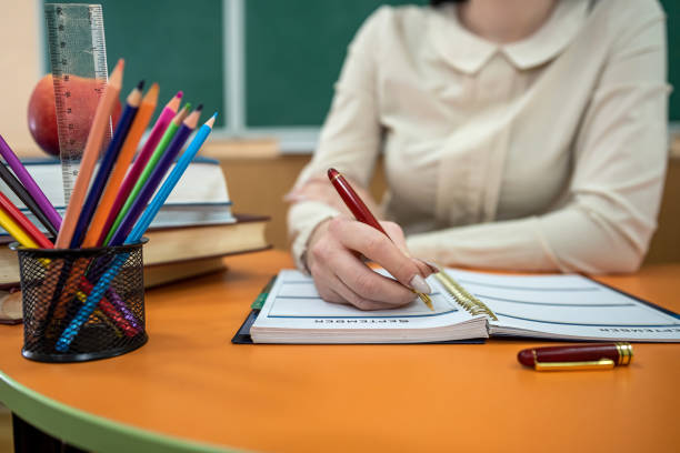 istock Woman teacher sits at a table with books and notebooks 1365213700