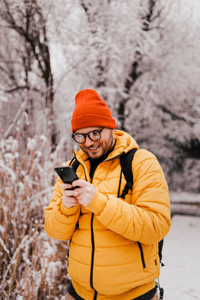 istock Young man using smartphone in nature on a snowy day 1365213727