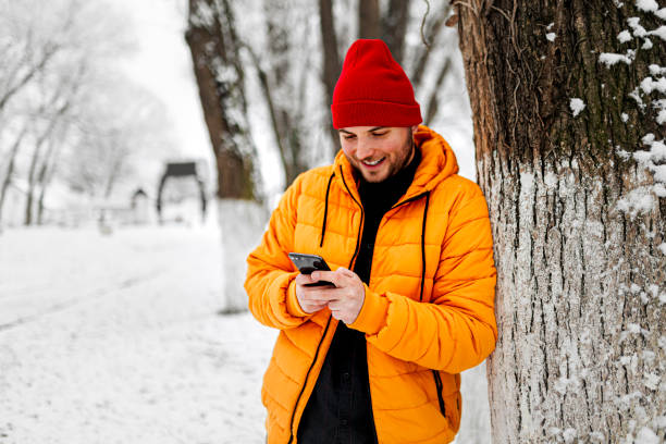istock Young man using smartphone in nature on a snowy day 1365213934