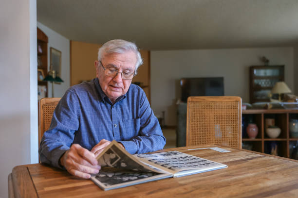 istock Elderly man looking at his high school yearbook 1365214007