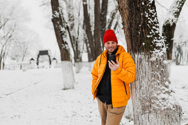 istock Young man using smartphone in nature on a snowy day 1365214014