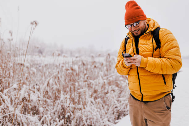 istock Young man using smartphone in nature on a snowy day 1365214068