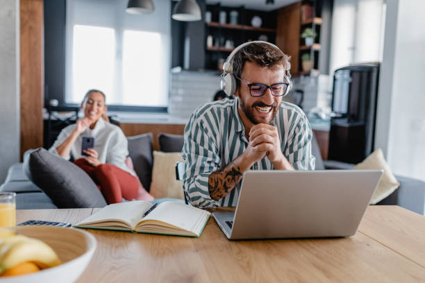 istock Young man with headphones is working from home on laptop 1365214973