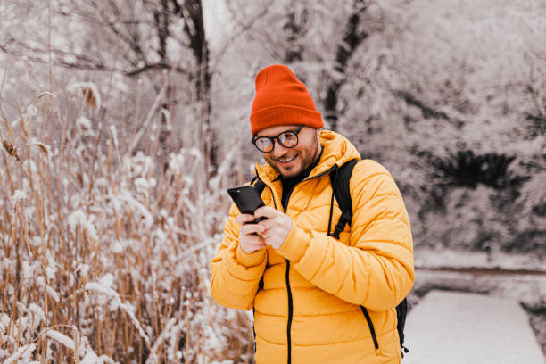 istock Young man using smartphone in nature on a snowy day 1365216635