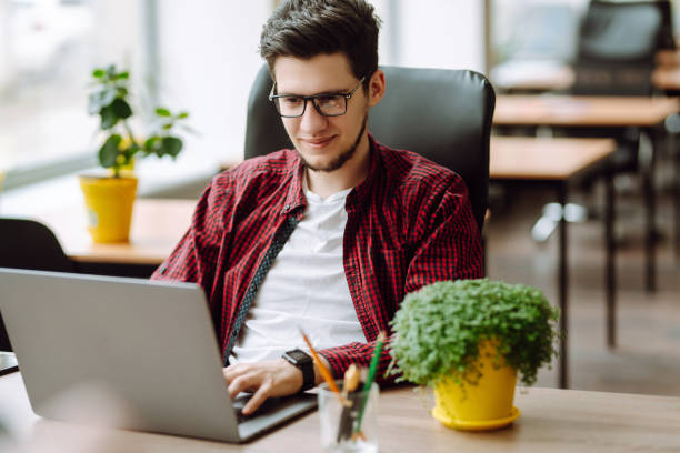 istock Education and working online. Young man with glasses working on laptop. Technology, 1365216644