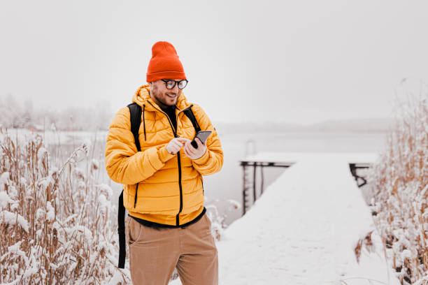 istock Young man using smartphone in nature on a snowy day 1365216829