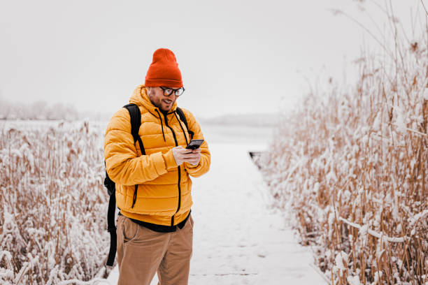 istock Young man using smartphone in nature on a snowy day 1365217030