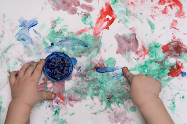 istock child draws with fingers, colored paints on white paper, close-up, selective focus 1365219790