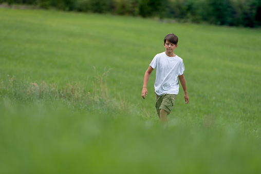 A happy teenager happily plays with a children's glider model in a country, green countryside or park.