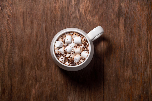 Mug of hot chocolate with marshmallow on the wood background directly above