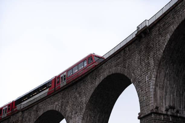 istock Passenger train crossing stone arch railway bridge in high key 1365228947