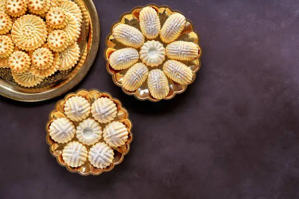 Photo of Assorted semolina maamoul or mamoul cookies with dates , walnuts and pistachio nuts. Traditional arabic Eid al Adha, Eid al Fitr sweets   . Top view, copy space