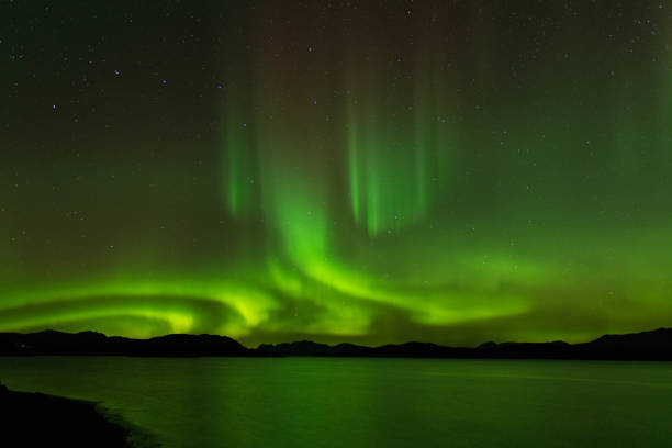 aurora borealis over lake in canada - mountain reflection non urban scene moody sky imagens e fotografias de stock