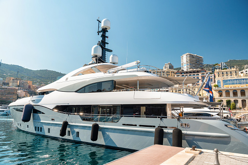 Moored yacht in Monaco. Sea port, multiple buildings and hills on the background