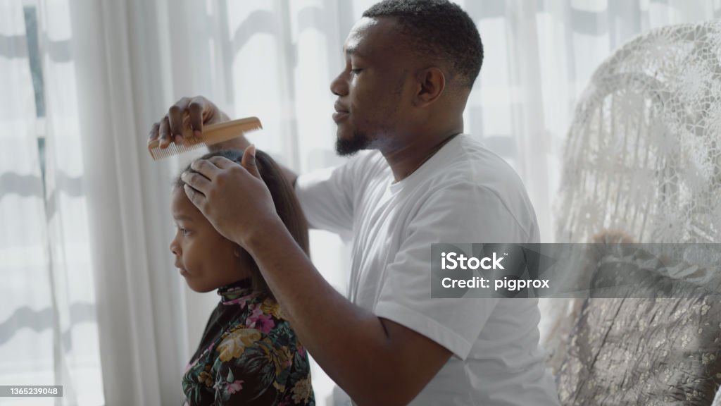 Father combing daughter's hair Father combing his daughter with love in live room. Hair Stock Photo