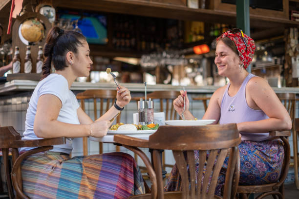 istock Two young women sitting and eating in a restaurant 1365241396