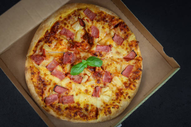 istock Round baked pizza in a craft box on a black 1365242883