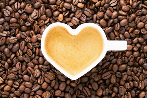 Heart shaped coffee beans on brown paper background.
