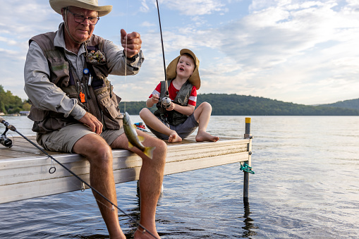 Happy senior father talking to his son while after fishing in nature. Copy space.