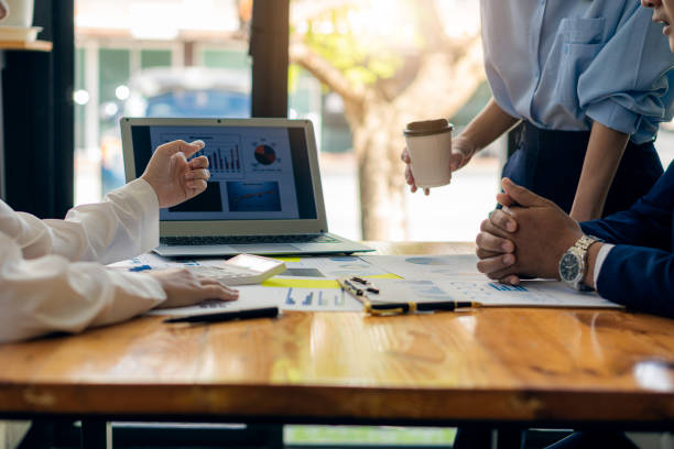 istock Businessman Discussing Successful Teamwork Teamwork Charts and Graphs Businessman working in the office discussing papers and ideas in meeting with laptop and calculator to calculate and analyze. 1365251443