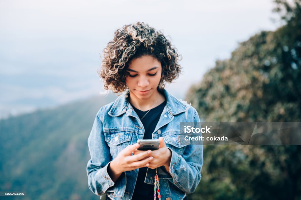 Teenager using cell phone outdoors Using Phone Stock Photo