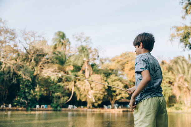 A boy puts bait on a fishing hook. Sport fishing on the river in summer.