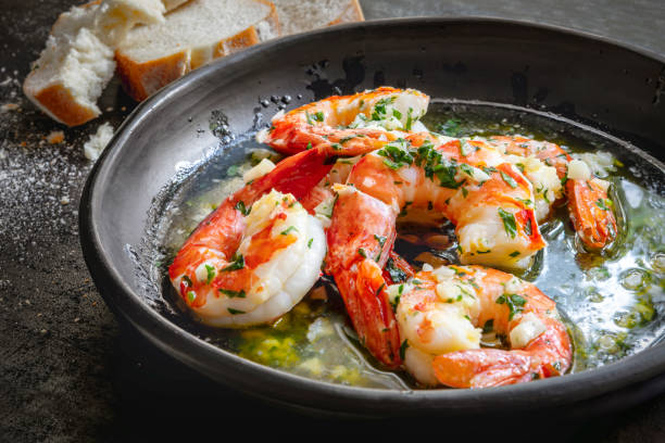 Garlic Prawns or Shrimp in black rustic bowl with crusty bread