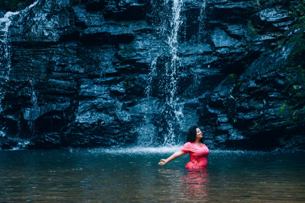 istock Young woman enjoying the waterfall 1365263190