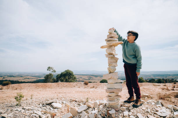 Boy building large rock totem