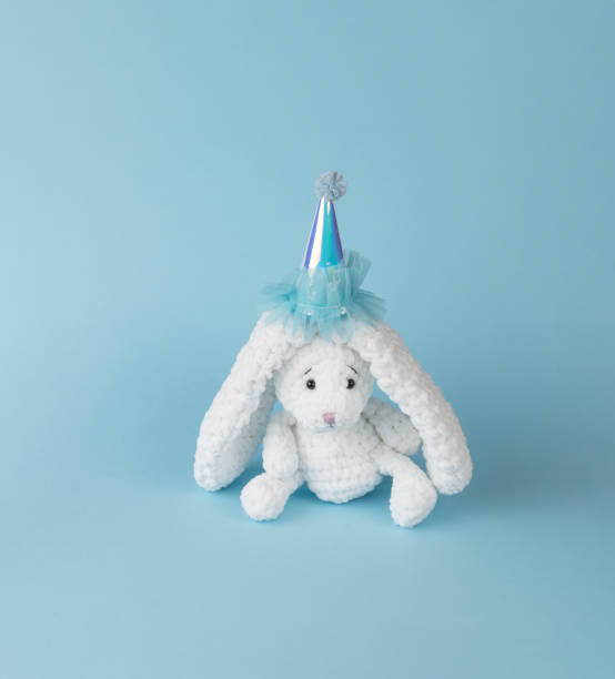 istock A white knitted bunny peeking out of a gift box on a blue background. 1365272783